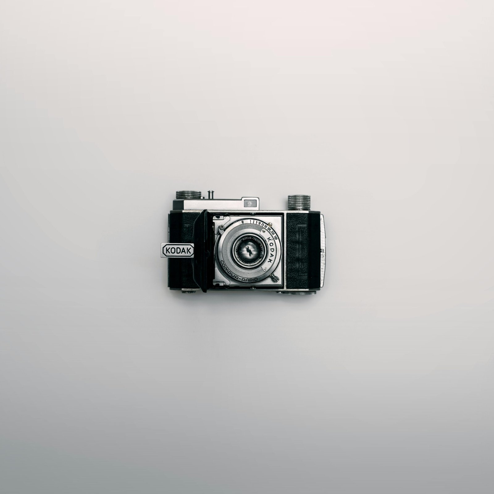 A classic Kodak camera displayed centrally on a minimalist white background.